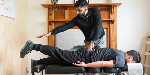 Chiropractor conducting a therapeutic spinal adjustment on a patient lying face down on a treatment table in a clinical setting.