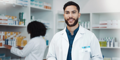 Portrait of a smiling male pharmacist using a tablet to check online inventory and manage supplies in a modern pharmacy.