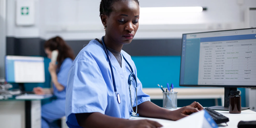 Nurse comparing data in a medical office, analyzing patient information to assist with healthcare decisions.