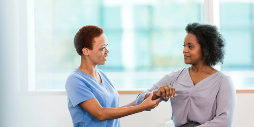 Occupational therapist helping a businesswoman recover from an arm injury, providing rehabilitation and care.