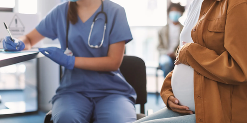 Pregnant lady wearing a mask during a doctor's appointment, focusing on prenatal care and health checks.