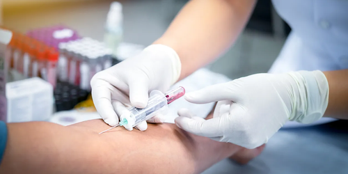 Healthcare professional taking a blood sample from a patient in the hospital for medical testing.