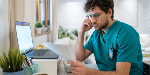 Concerned young Caucasian doctor examining medical test results in a clinical setting, looking worried about the findings.