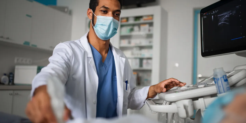 Young doctor examining a patient using ultrasound equipment in a clinic, conducting a non-invasive diagnostic procedure.